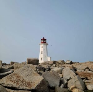 white and red lighthouse on gray rocky shore during daytime